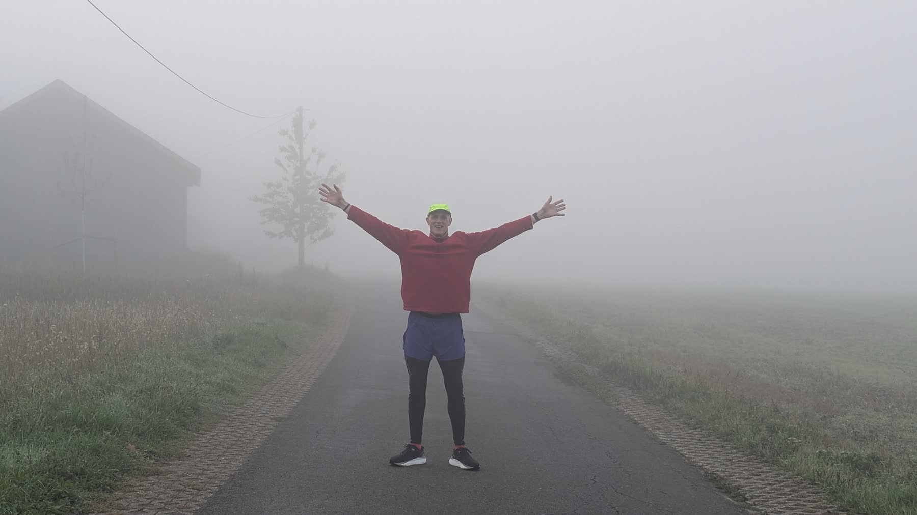 Runner standing on a foggy country road