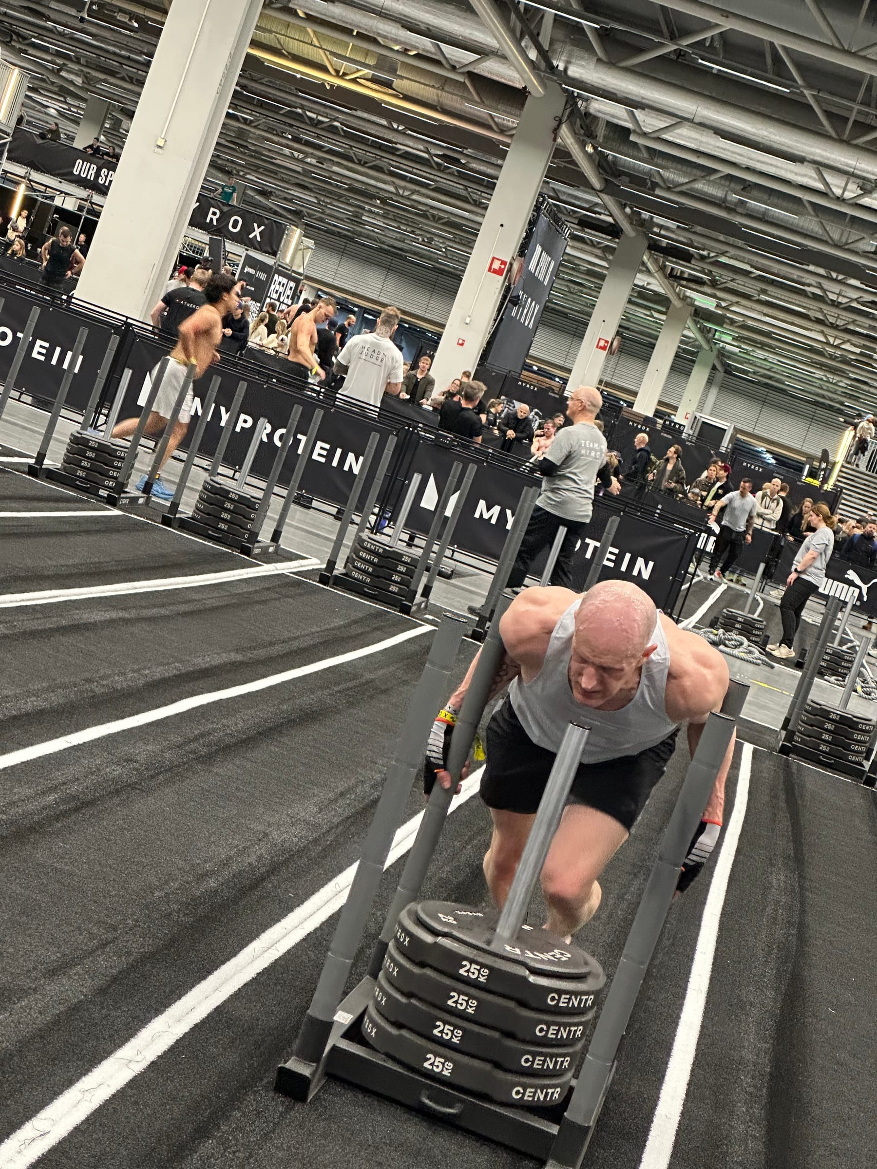 Age-group HYROX athlete pushing the sled during a race