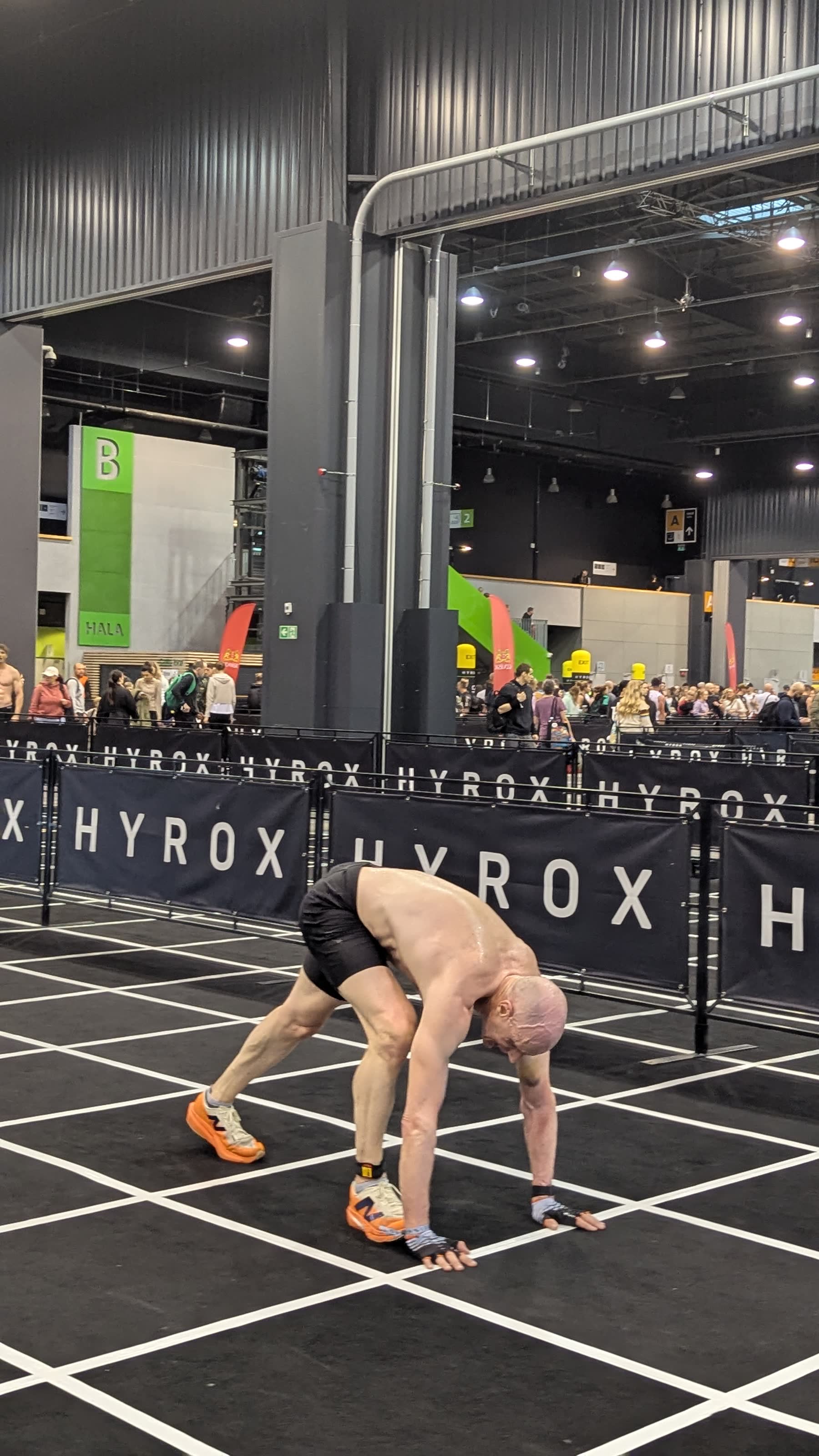 HYROX athlete during burpee broad jumps in a race venue